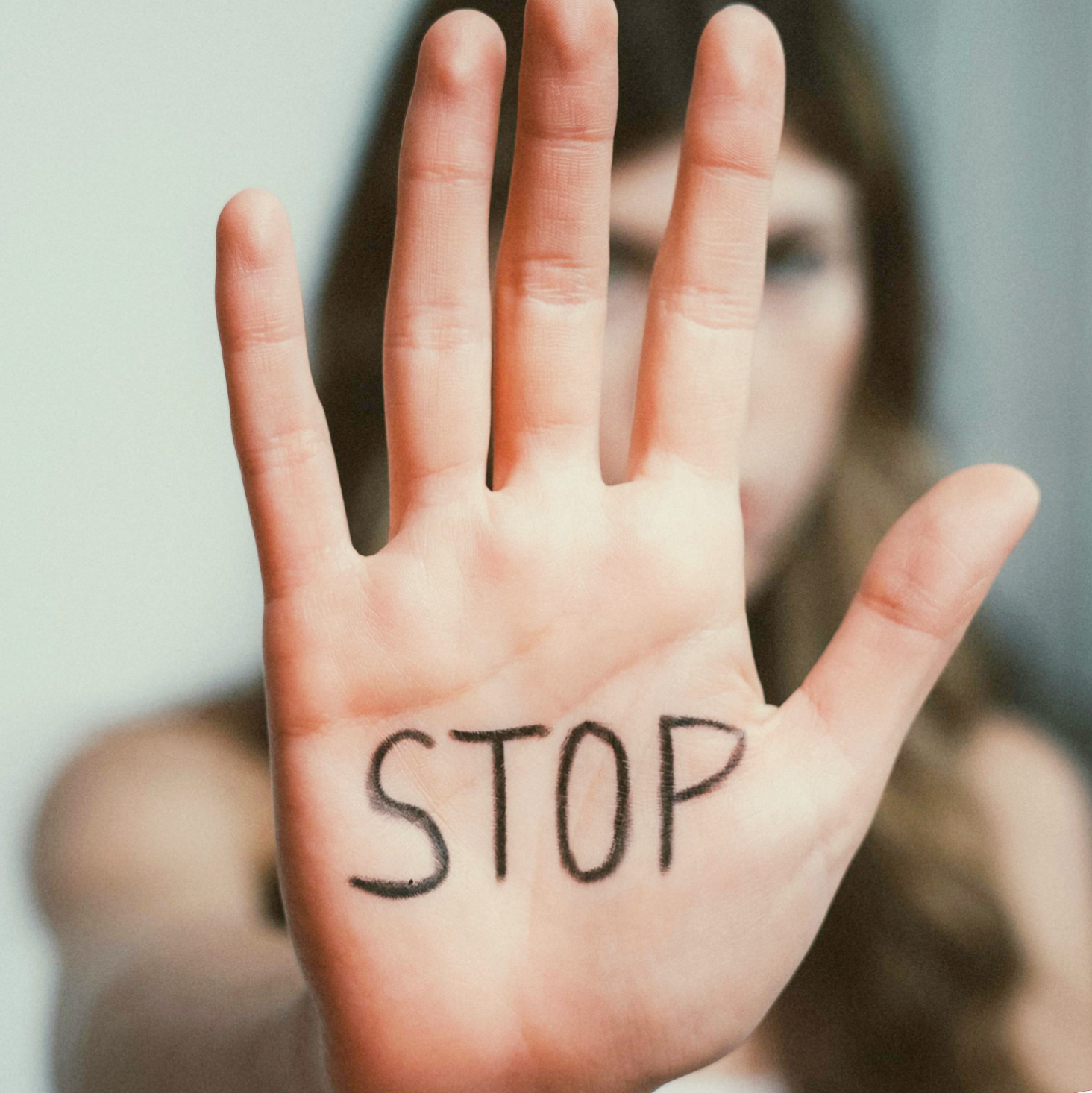 Frau streckt die Hand mit der Aufschrift Stop in die Kamera